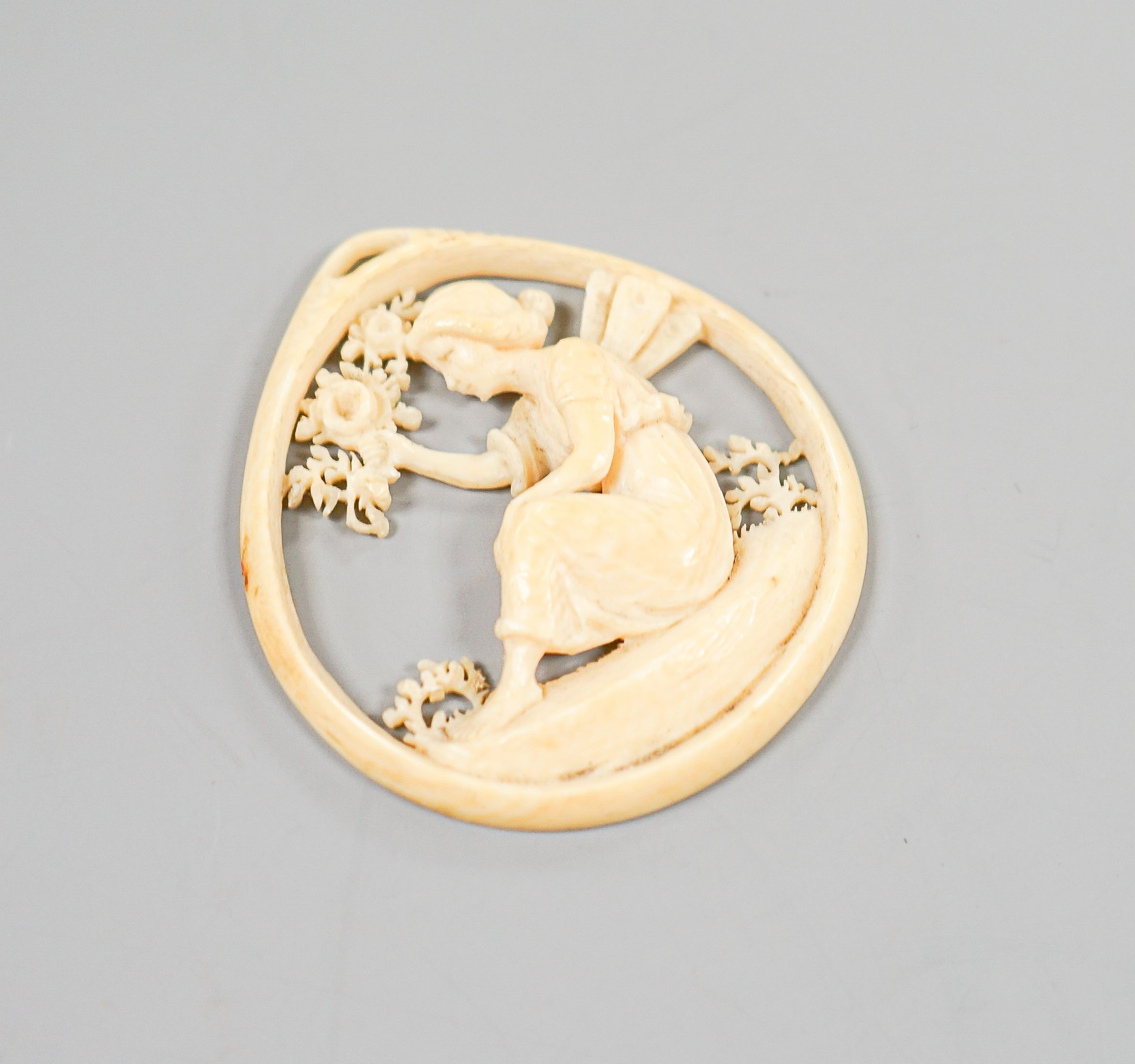 A carved ivory pendant, modelled as a seated fairy, 50mm.